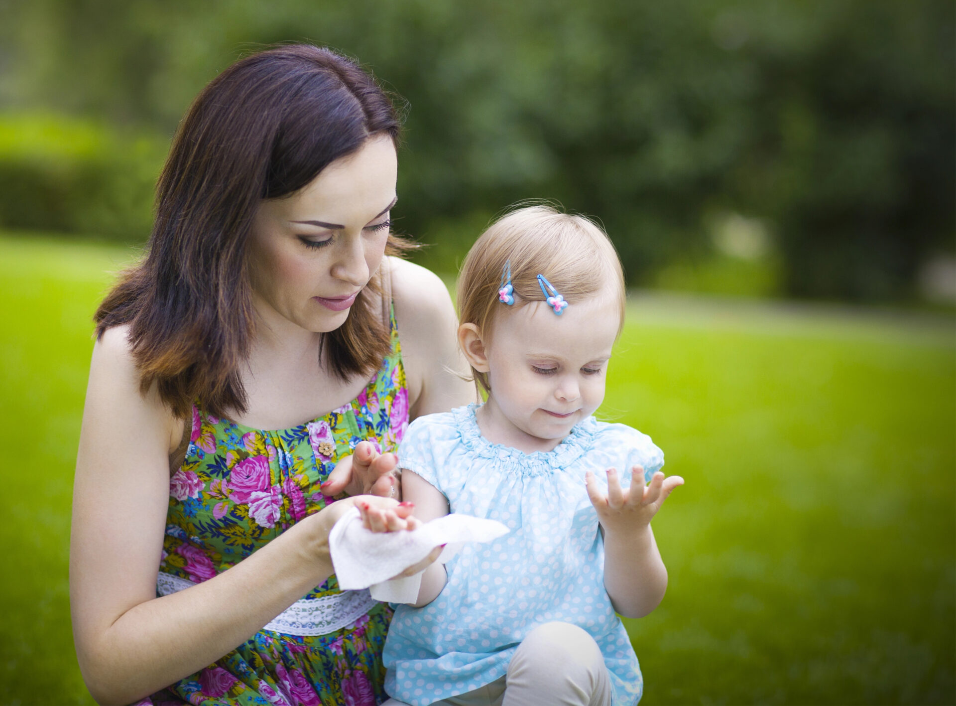 Mom cleaning food off hands of toddler using a baby wipe