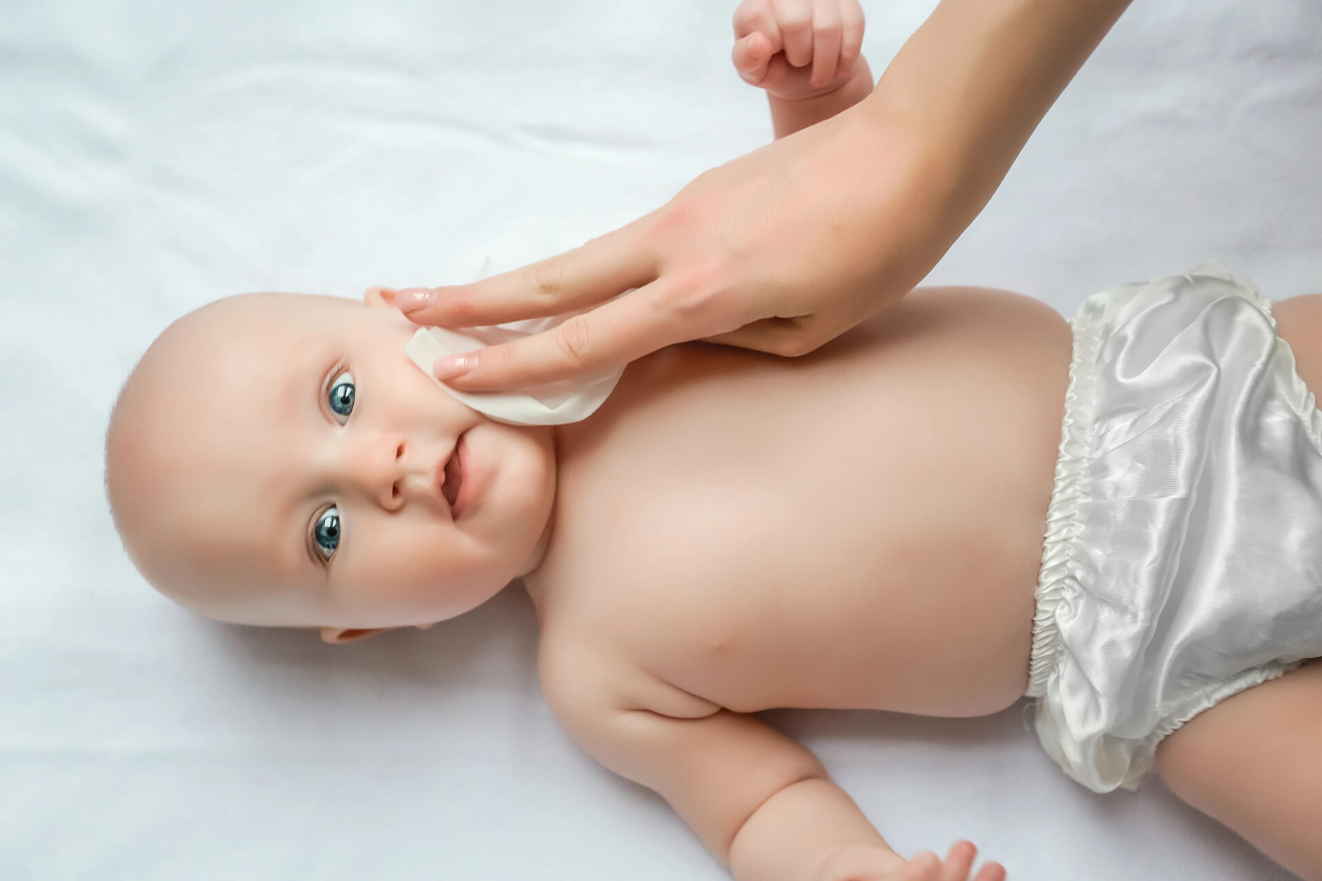 Mom cleaning baby's face with baby wipe